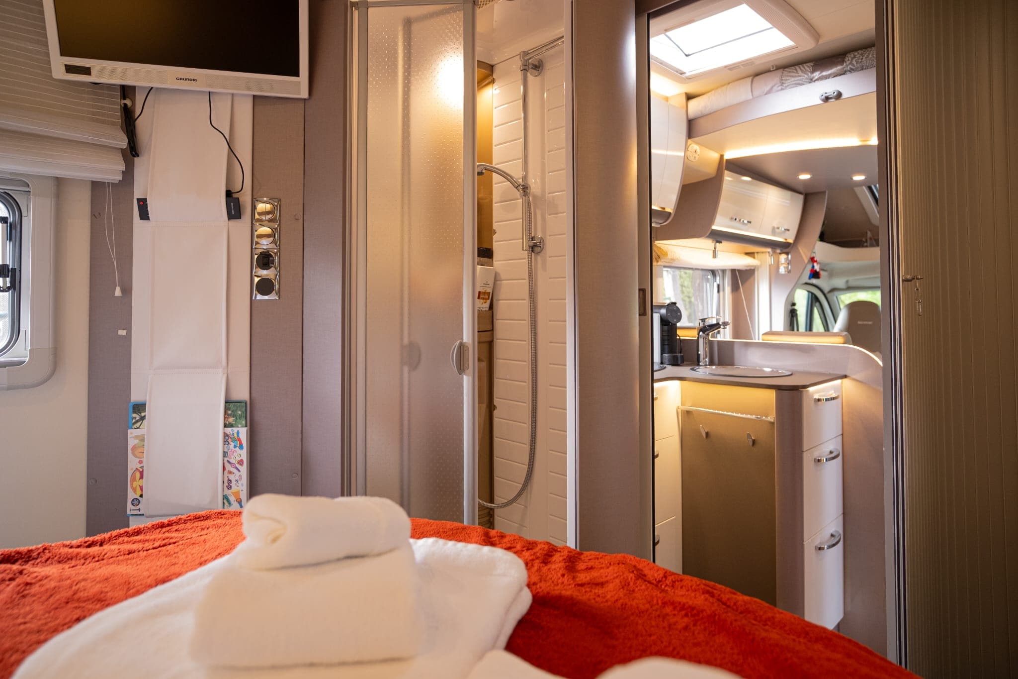Quarto com televisão e cama feita com manta laranja